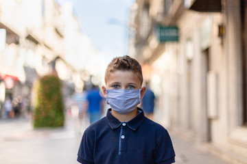 Fototapeta na wymiar Kid with medical mask in the street. Little boy with face mask. Coronavirus pandemic concept