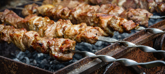 Traditional eastern dish, shish kebab. Grilled kebab cooking on metal skewer. Roasted meat cooked at barbecue. BBQ fresh beef meat chop slices. Grill on charcoal and flame, picnic, street food.