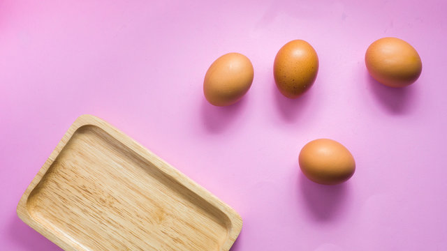 Eggs on a pink bckground with wooden tray