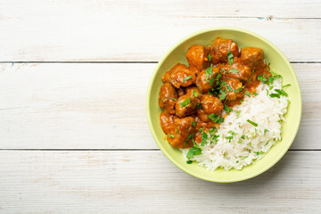 Meat stew with white rice on rustic wooden background