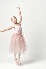 Naklejka premium Girl ballerina in pink dance costume ballet dance pointe shoes tutu light background model