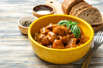 Meat stew in ceramic bowl on rustic wooden background