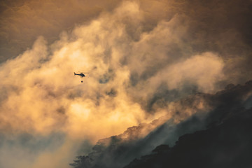 Fire fighting helicopter carry water bucket to extinguish the forest fire