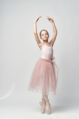 Fototapeta na wymiar Girl ballerina in pink dance costume ballet dance pointe shoes tutu light background model