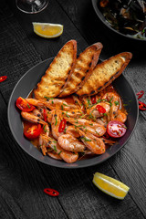 Fried shrimps in garlic sauce on a black board table