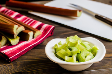 Rhubarb on wooden table. Fresh rhubarb on white bowl.
