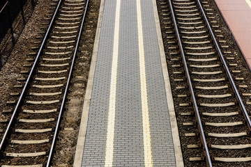 Obraz premium Railway top view background. Train transport industry. Rail track texture. Good and cheap way of transportation for cargo. Track ballast gravel made of crushed stone. Empty train station platform.