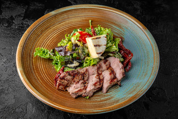 Gourmet hot salad made with pieces of pork or grilled duck, camembert cheese, sun dried tomatoes, herbs and sauce. Balanced dietary nutritious food.