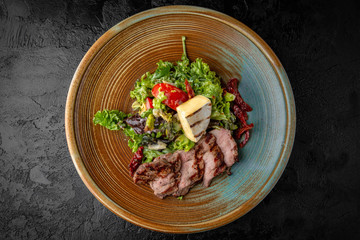 Gourmet hot salad made with pieces of pork or grilled duck, camembert cheese, sun dried tomatoes, herbs and sauce. Balanced dietary nutritious food.