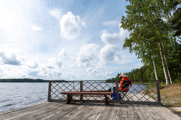 Woman relaxes on lake pier and reads a book 