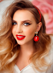 Beauty Portrait of girl with perfect makeup and red jewelry. Beautiful model woman with long curly hairstyle. Eyelashes. Cosmetic eyeshadow. Care and beauty face products.