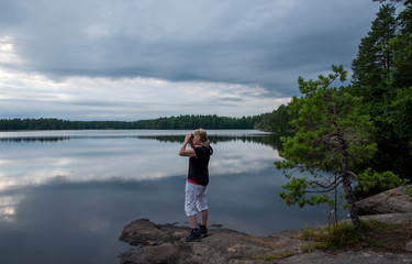 Woman using binoculars while a hiking in the lake