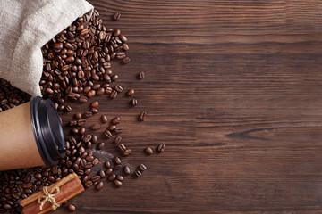 Coffee beans, coffee mug and cinnamon on a wooden background.