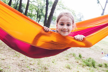 Fototapeta na wymiar Happy portrait of little girl relax on hammock in forest