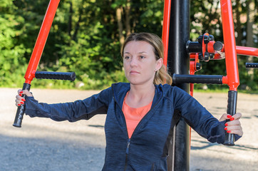 Young women doing sports on outdoor exercise machine in the stadium