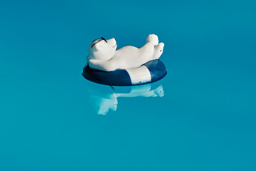 Pool decoration in the form of a relaxed bathing polar bear with sunglasses and a swim ring on blue...