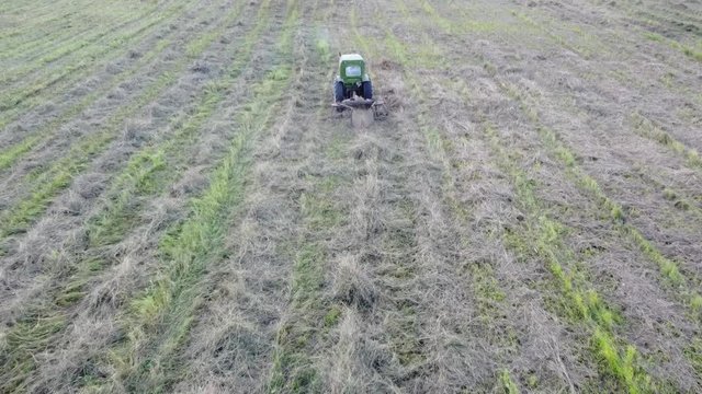 tractor with tedder collects hay in one line