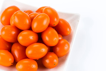 Close-up of fresh cherry tomatoes on a white dish.