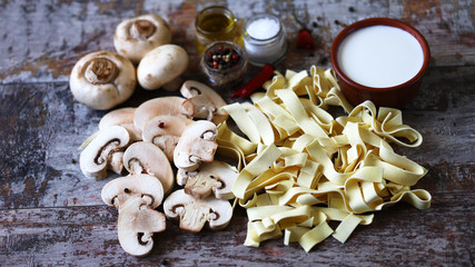 Ingredients for pasta with mushrooms in a creamy sauce. Raw pasta, champignons, cream, spices. Cooking pasta.