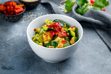 broken cucumbers with peanuts on grey table