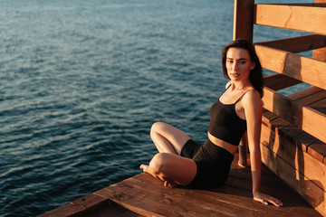 Fototapeta na wymiar Image of young beautiful girl in sportswear posing near sea