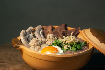 Porridge rice or Congee with egg, pork entrails and ginger slide in a clay pot isolated on Dark Slate Gray Concrete Wall background
