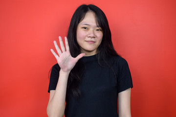 Portrait of Young beautiful asian woman using black T-shirt with red isolated background