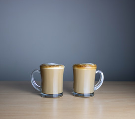 Glass cup of coffee with milk on a wooden table. Milk foam. Espresso coffee with milk.