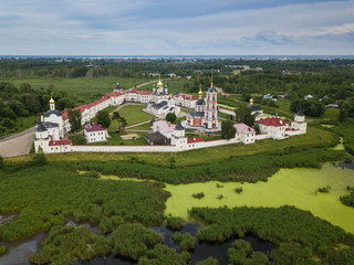 Aerial summer view of white old monastery with golden domes among green fields in Rostov the Great...