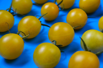 Yellow cherry tomatoes pattern on bright blue background.Minimal concept.Selective focus.