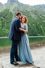 young couple on a walk near the lake surrounded by the mountains