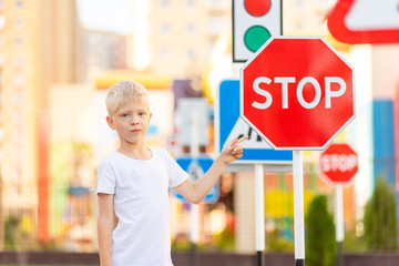 a child stands at a stop sign and points at it with his finger, traffic rules for children