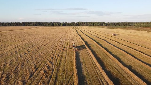 tractor with tedder collects hay in one line
