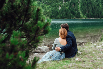 young couple on a walk near the lake surrounded by the mountains