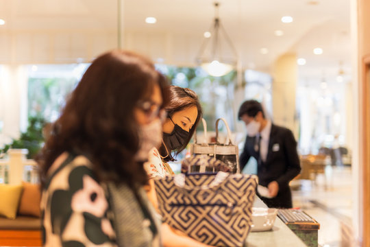 Woman Client Signing Hotel Contract Paper At Reception Desk In Face Mask.