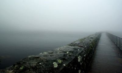 A disappearing dam wall on a misty day