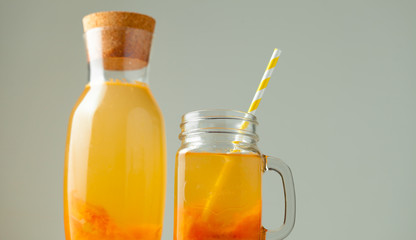 Orange fresh fruit beverage in the glass jar on the summer white background