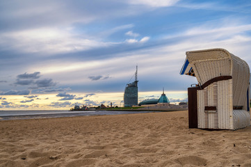 Blick entlang der Küste von Bremerhaven mit Sandstrand im Vordergrund und Bauwerken und Hafen im...