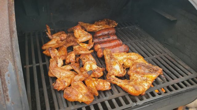Home cooking - High angle close  up of chicken wings and sausage  being smoked for extra smoky flavor after previously cooked in gas grill.