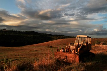 Sunset on the Tuscan Maremma. Old agricultural machine in the foreground.