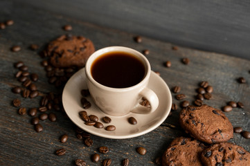 Coffee cup with cookies on wooden table background. Mug of black coffee with chocolate cookies. Fresh coffee beans.