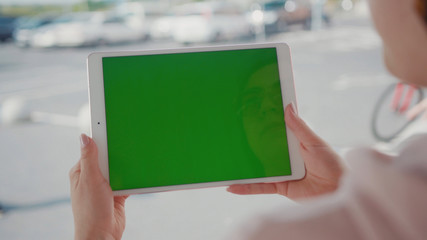 Close up hands woman using tablet device computer with green screen outdoors in street at sunlight horizontal bloom message pad technology chroma key female digital girl app chat finger mock up