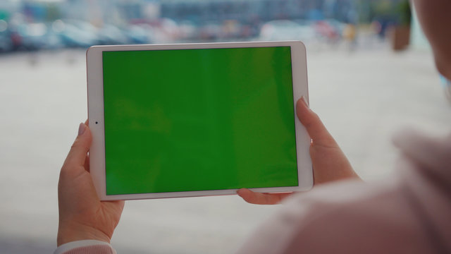 Close up hands woman using tablet device computer with green screen outdoors in street at sunlight horizontal bloom message pad technology chroma key female digital girl app chat finger mock up