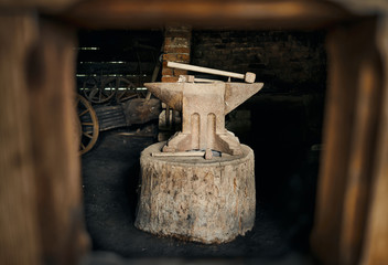 Fototapeta na wymiar Old rusty anvil and three hammers placed on tree stump at the blacksmith's.