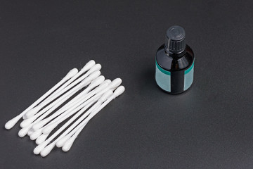 Naklejka premium Top view of cotton swabs and a bottle of antiseptic on a black background close up