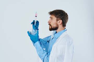 man in medical gown laboratory assistant with liquid in flask and stethoscope doctor chemical reaction light background