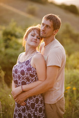 Happy young woman and man in romantic relationship hugging and kissing at sunset.