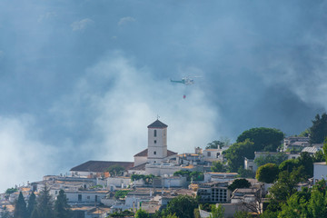 Helicopter with a water bag working to extinguish a fire in Las Alpujarras de Granada.