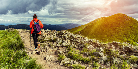 Girl hiking in mountains at sunset. Hiking trail in Bieszczady Poland. Lonley hiker in the mountains. Woman conquer mountains.