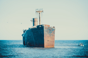 A shipwreck on a sandbank in the sea. Rusty wreck abandoned at sea.